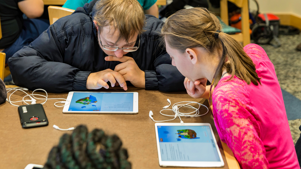 Two kids are playing with the Swift Playgrounds app on their iPads